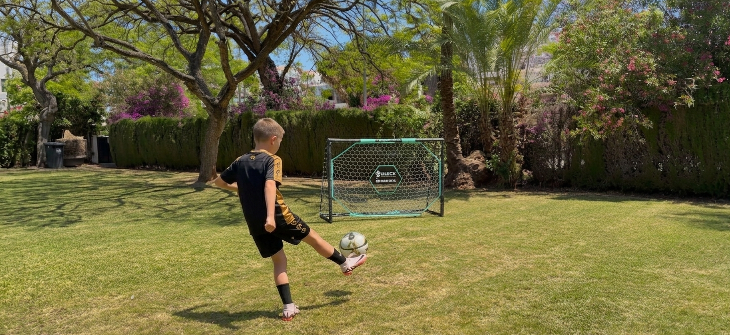 Niño realizando ejercicios de tiro a puerta con portería Mainake Hércules en jardín doméstico
